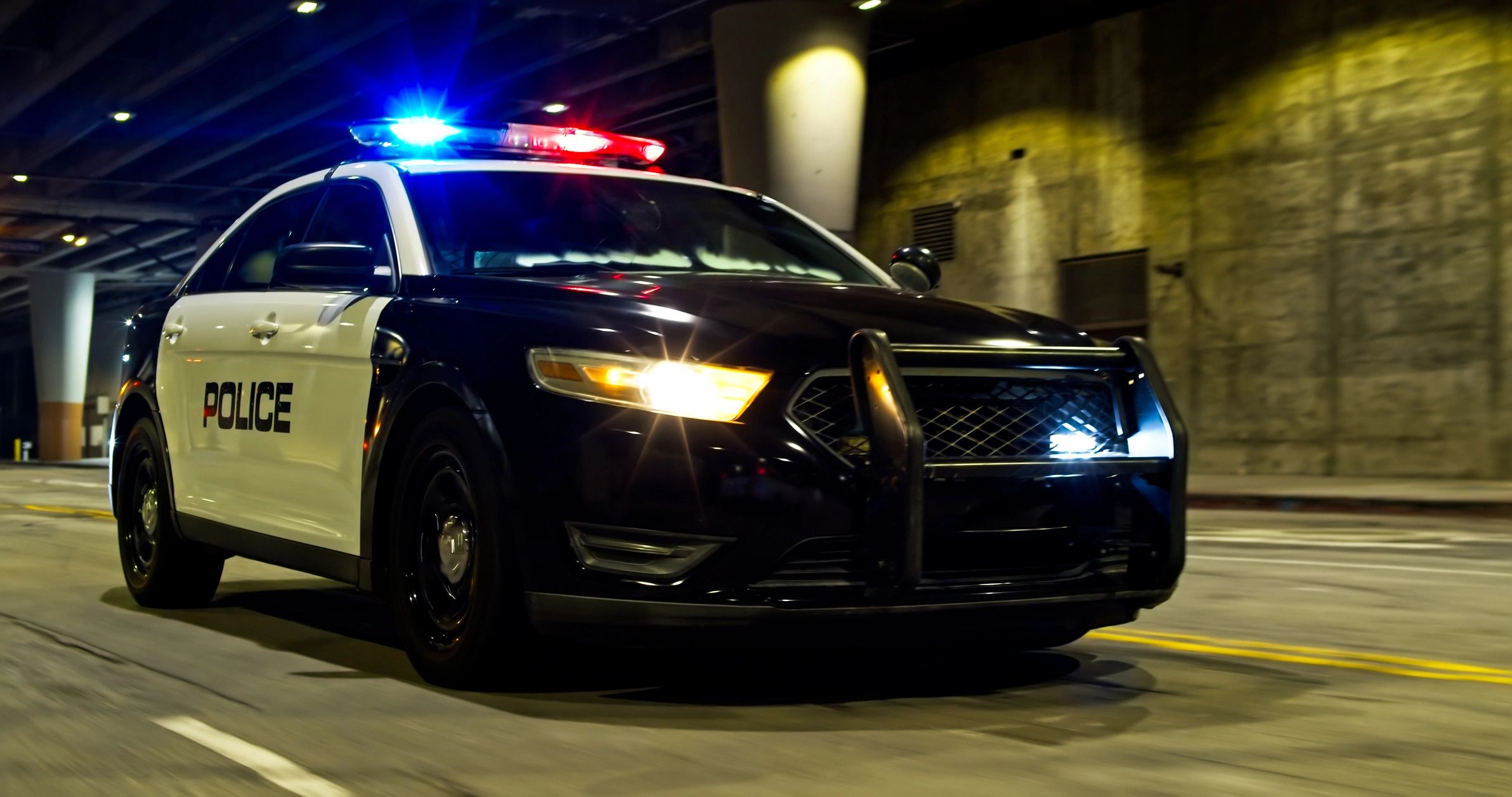 Police car with lights on at night in a city underpass