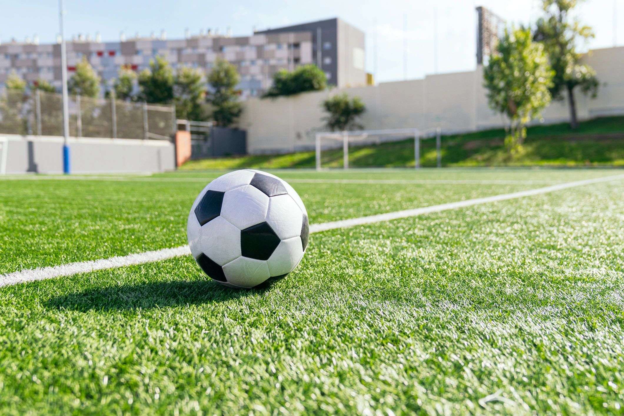 Soccer ball on green turf with goal in background